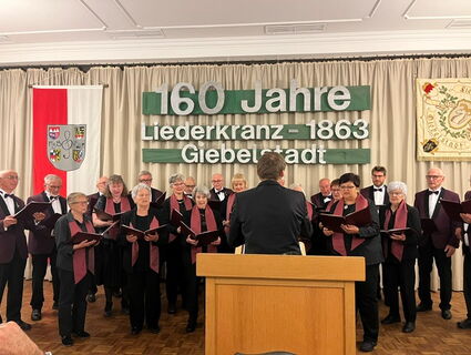 singender Chor, dahinter in großen Lettern "160 Jahre Liederkranz 1863 Giebelstadt"